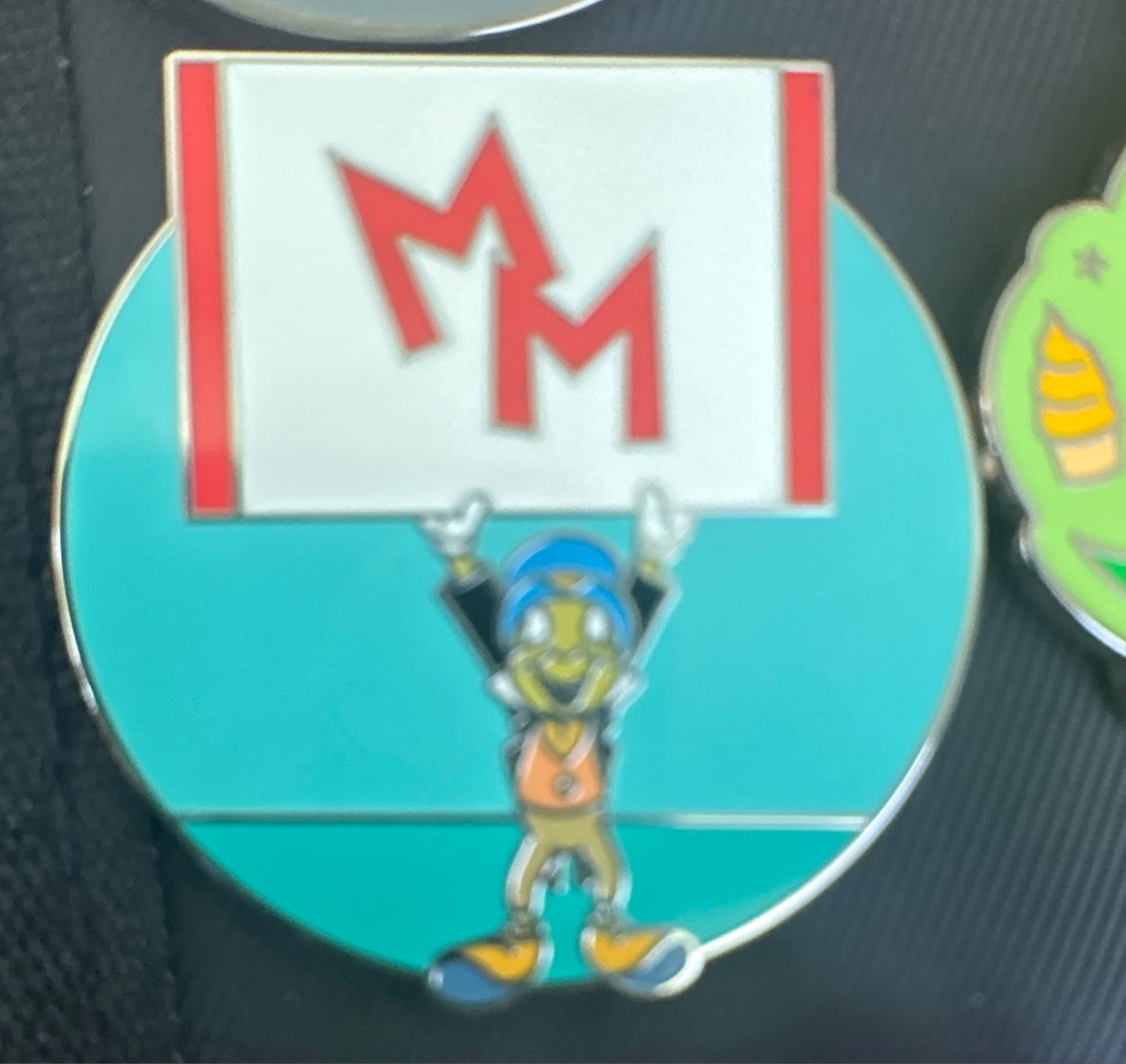 Jiminy Holding 'MM' Sign front